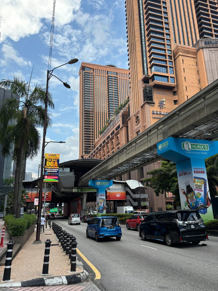 Family choosing transportation options in Malaysia (private car, trains, Grab)” · AR: “عائلة تختار وسائل النقل في ماليزيا (سيارة خاصة، قطارات، جرب)”