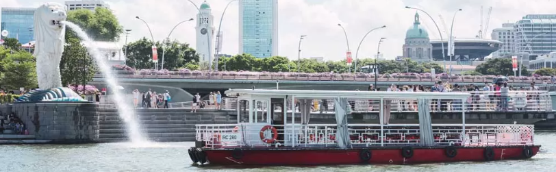 Sightseeing boat cruising at sunset on the Singapore River Cruise toward Marina Bay